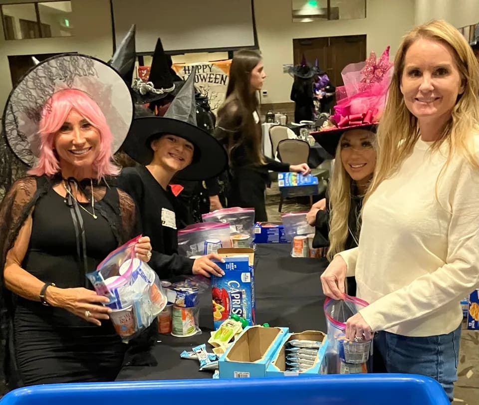 Witches packing snacks into meal kits at the assembly table