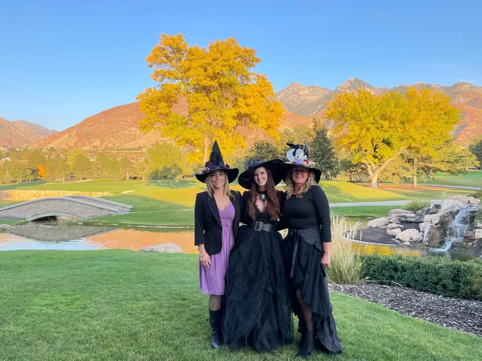 Three witches on the Willow Creek Country Club patio with the golf course and fall mountains behind