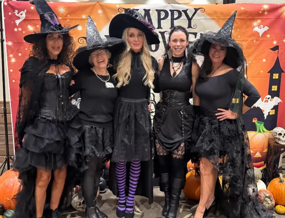 Five witches posing at the Happy Halloween backdrop